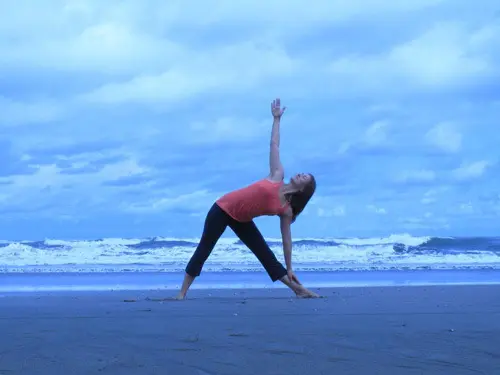 woman doing triangle pose on a beautiful sea beach