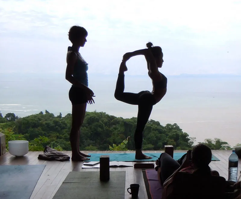 A participant is practicing Lord shivas pose under the guidance of an instructor in Anamaya Yoga Resort