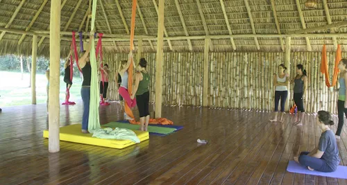 women practicing aerial yoga at wooden yoga deck