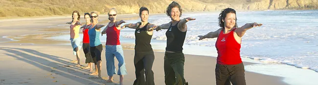 women doing warrior pose on a sea beach