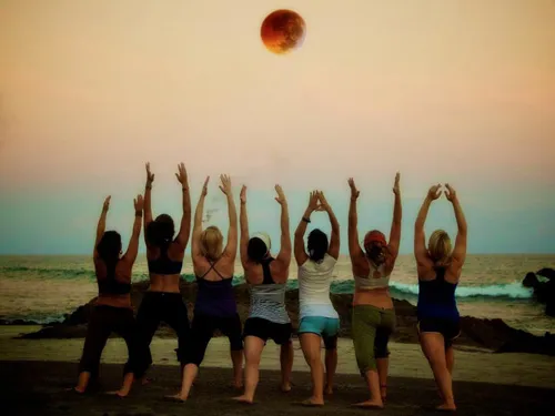women doing warrior pose on a sea beach