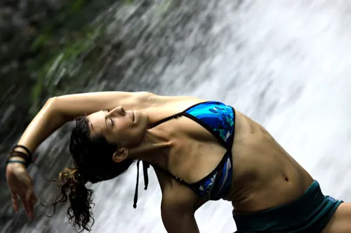 beautiful woman doing yoga beside a waterfall
