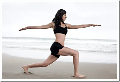 woman doing warrior pose on the beach